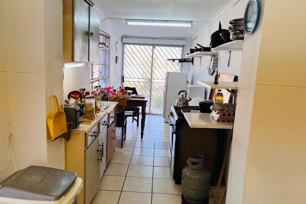 A functional galley-style kitchen featuring tiled flooring, built-in cabinetry, and a gas stove, with direct access to the exterior via a sliding glass door.