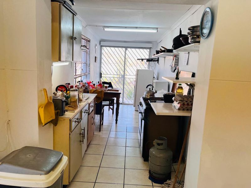 A functional galley-style kitchen featuring tiled flooring, built-in cabinetry, and a gas stove, with direct access to the exterior via a sliding glass door.