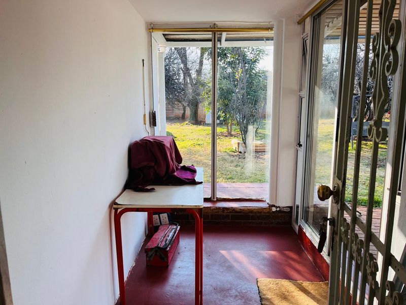 A sunroom or enclosed patio area featuring a painted concrete floor, sliding glass doors, and direct access to the rear garden.