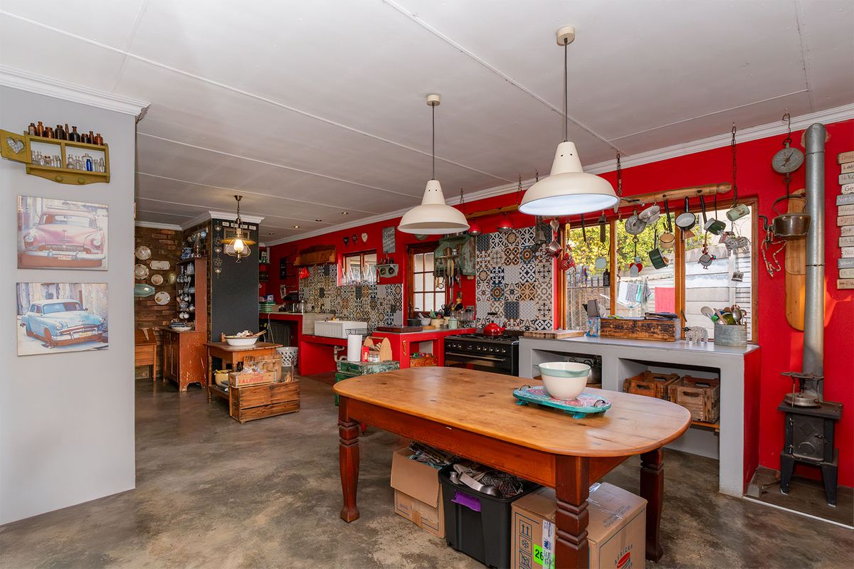 Spacious kitchen featuring a farmhouse sink, gas stove, wood-burning fireplace, and unique tiled splashback with concrete flooring.