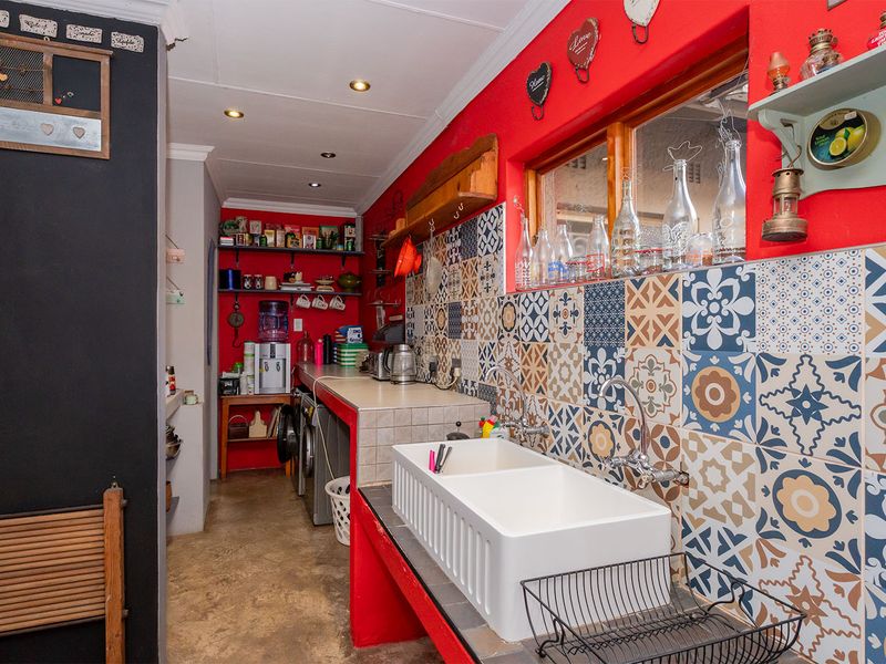 A functional laundry area featuring a double farmhouse sink, decorative patterned tile splashback, and built-in counter space with plumbing connections.