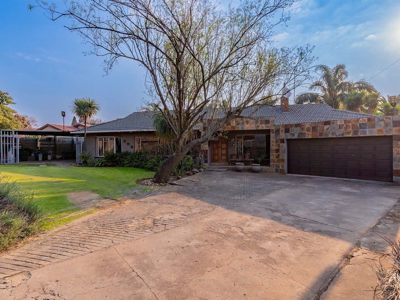 Front elevation of a single-story house featuring stone cladding, a tiled roof, a paved driveway, and an integrated double garage.
