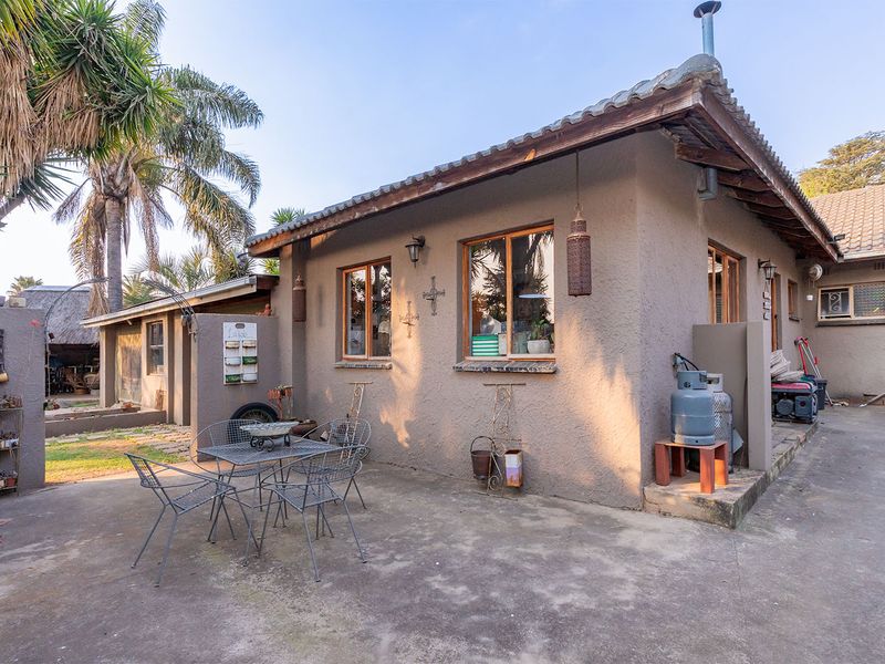 Rear exterior view of the house featuring a concrete patio area, stucco walls, and a tiled roof structure.
