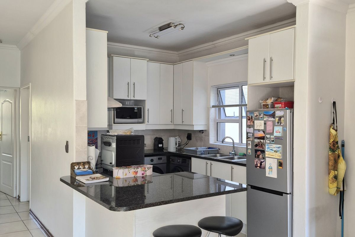 A functional kitchen featuring white cabinetry, granite countertops, a breakfast bar, and tiled flooring, providing a practical layout for daily meal preparation.