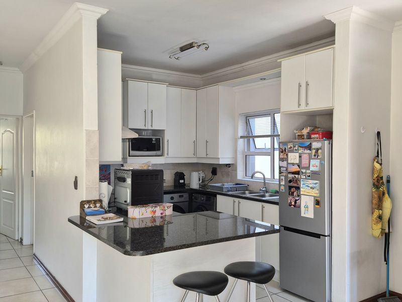 A functional kitchen featuring white cabinetry, granite countertops, a breakfast bar, and tiled flooring, providing a practical layout for daily meal preparation.