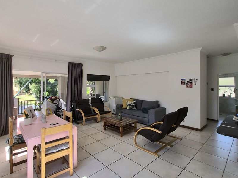 Spacious open-plan living and dining area featuring neutral tiled flooring and large sliding glass doors providing access to an outdoor balcony.