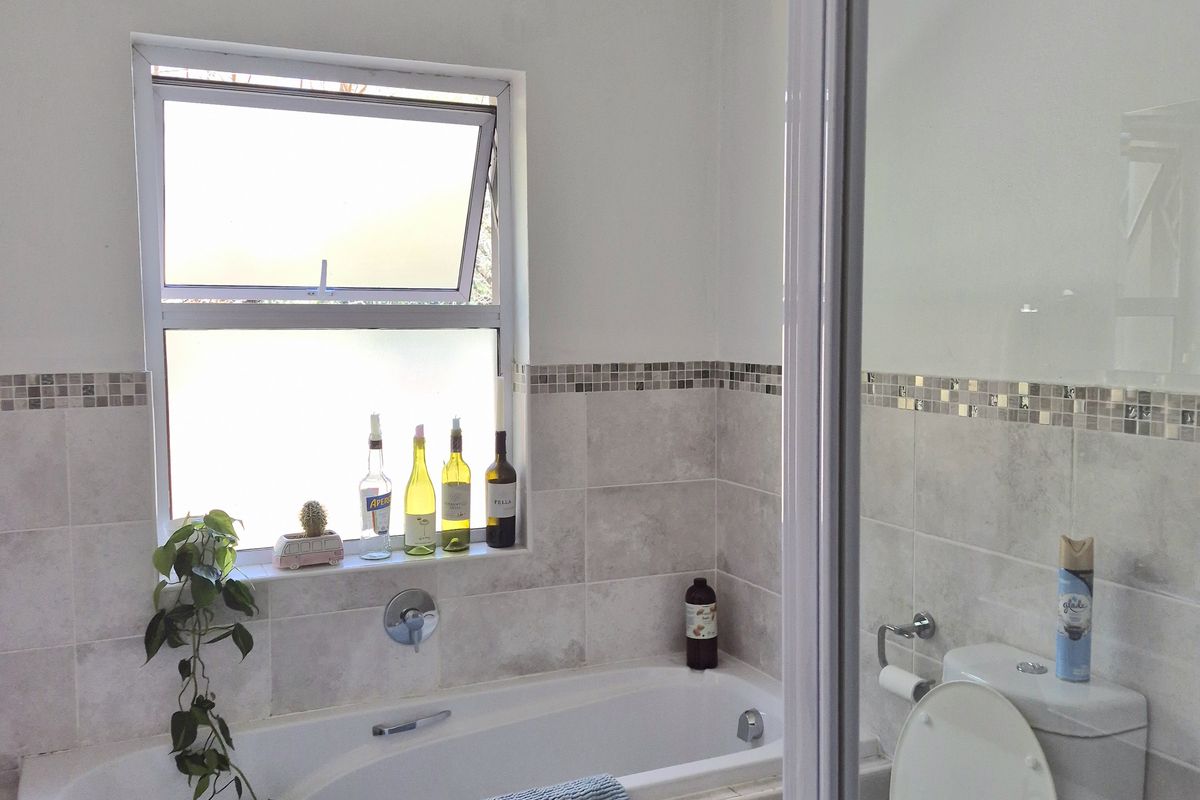 A functional bathroom featuring a built-in bathtub, a separate shower enclosure, and a toilet, finished with neutral wall and floor tiling.