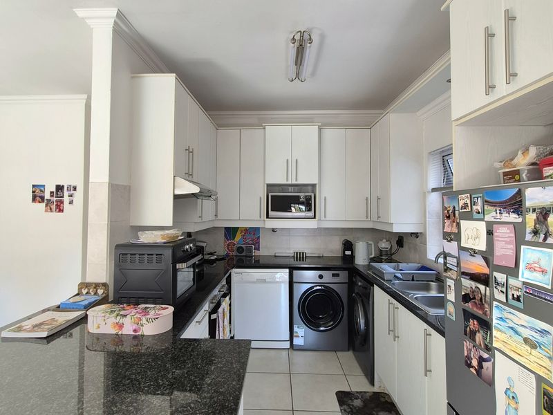 A functional kitchen featuring granite countertops, white cabinetry, and integrated appliances, offering a clean and practical layout for daily use.