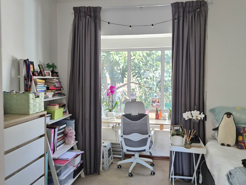 A well-lit bedroom featuring neutral carpet flooring, crown molding, and a large window with curtain tracks, providing a comfortable and functional living space.