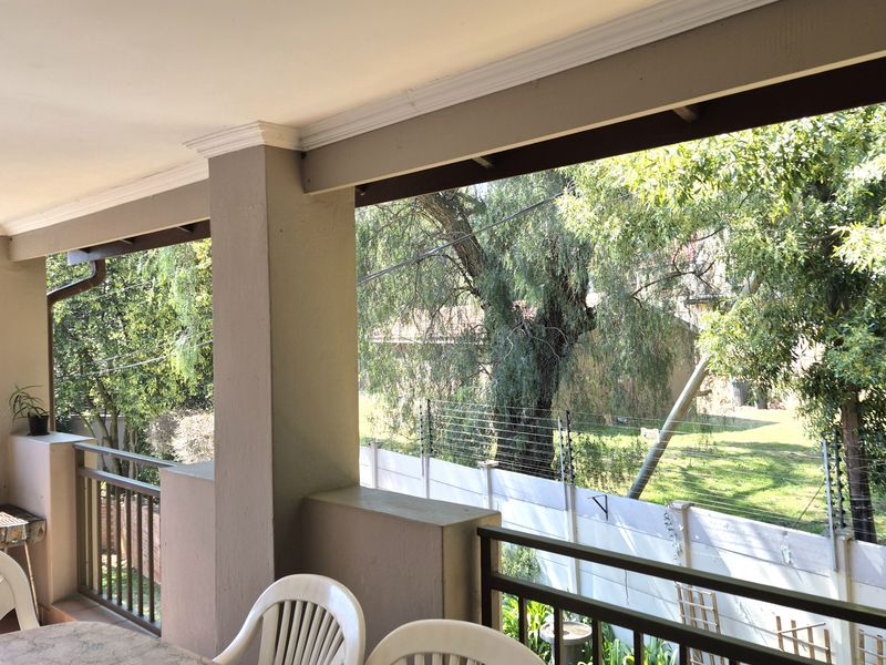 A covered balcony featuring a metal balustrade, recessed lighting, and views over the garden area.