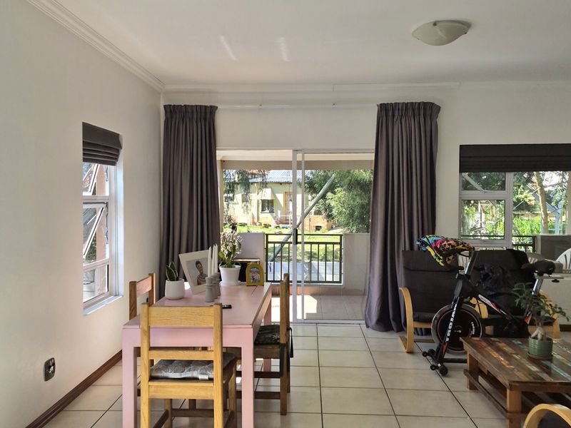 Bright open-plan living and dining area featuring neutral tiled flooring, large sliding doors leading to a balcony, and ample natural light.