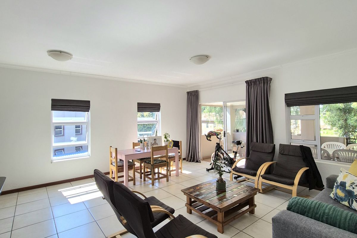 Spacious open-plan living and dining area featuring neutral tiled flooring, large windows for natural light, and direct access to an outdoor patio.