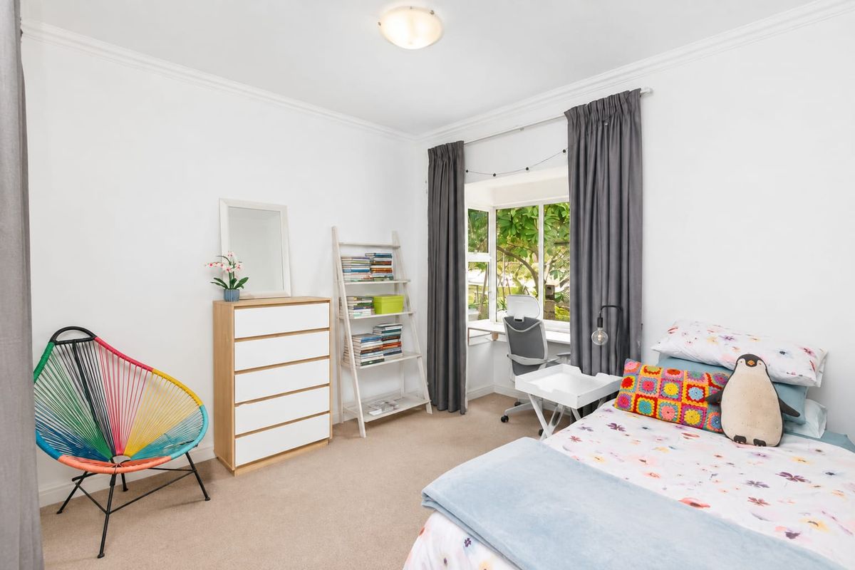 A bright and well-maintained bedroom featuring a bay window, neutral carpeting, and classic ceiling cornice detailing.