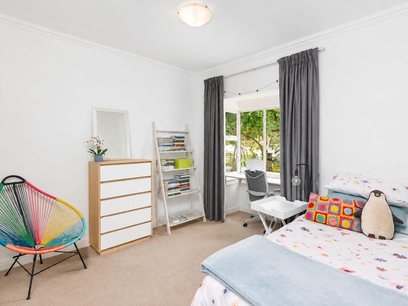 A bright and well-maintained bedroom featuring a bay window, neutral carpeting, and classic ceiling cornice detailing.