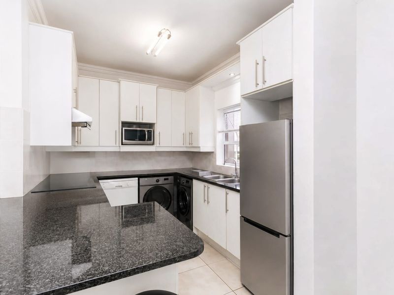 A modern, well-maintained kitchen featuring granite countertops, ample white cabinetry, and integrated appliances, offering a clean and functional workspace.