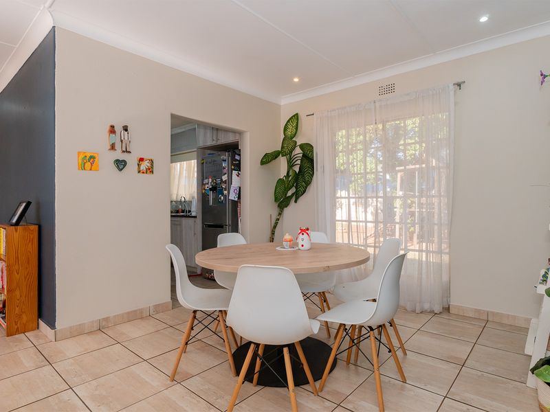 A bright dining area featuring neutral walls, tiled flooring, and a sliding glass door providing natural light and access to the exterior.