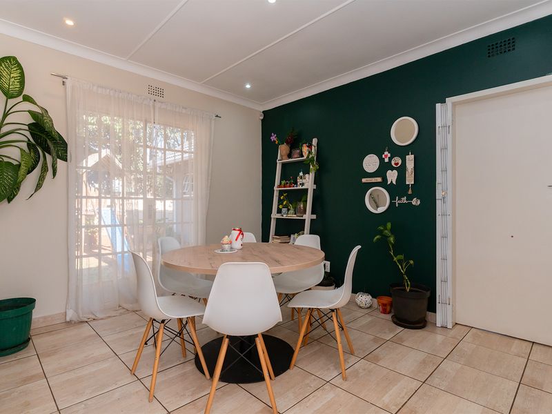 A bright dining area featuring tiled flooring, recessed ceiling lighting, and a sliding glass door providing natural light and access to the exterior.