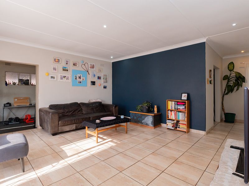 Spacious living room featuring neutral walls, a dark blue accent wall, tiled flooring, and recessed ceiling lighting.