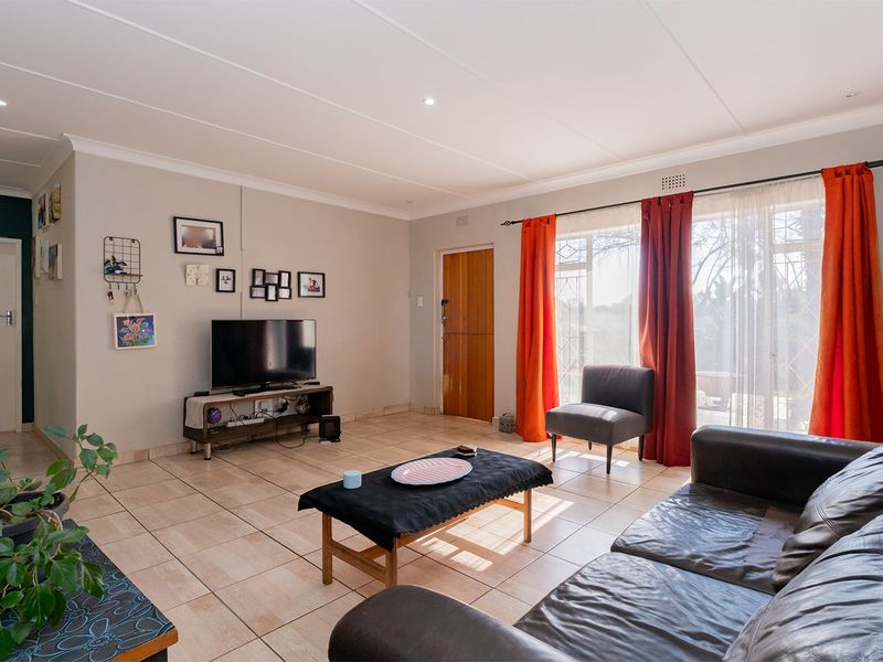 A bright living room featuring tiled flooring, recessed lighting, and a large sliding glass door providing access to the exterior.