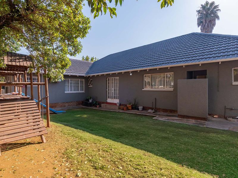 Rear view of the house featuring a tiled roof, lawn area, and direct access to the backyard.