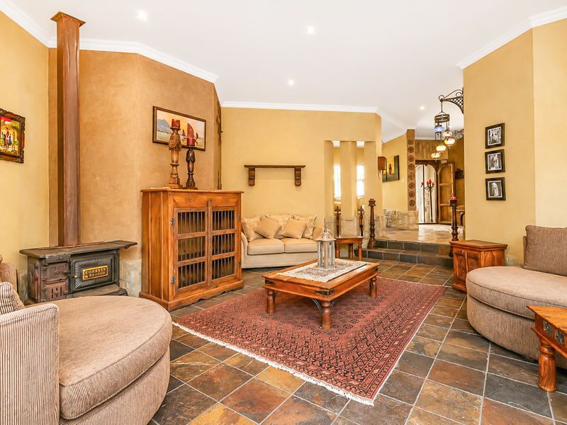 Spacious living room featuring slate tile flooring, a cast iron wood burning stove, and warm-toned walls with stone accents.