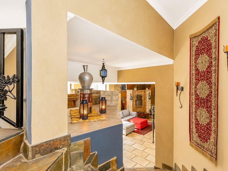 A view from a stone staircase looking down into a living area with vaulted ceilings and stone tile flooring.