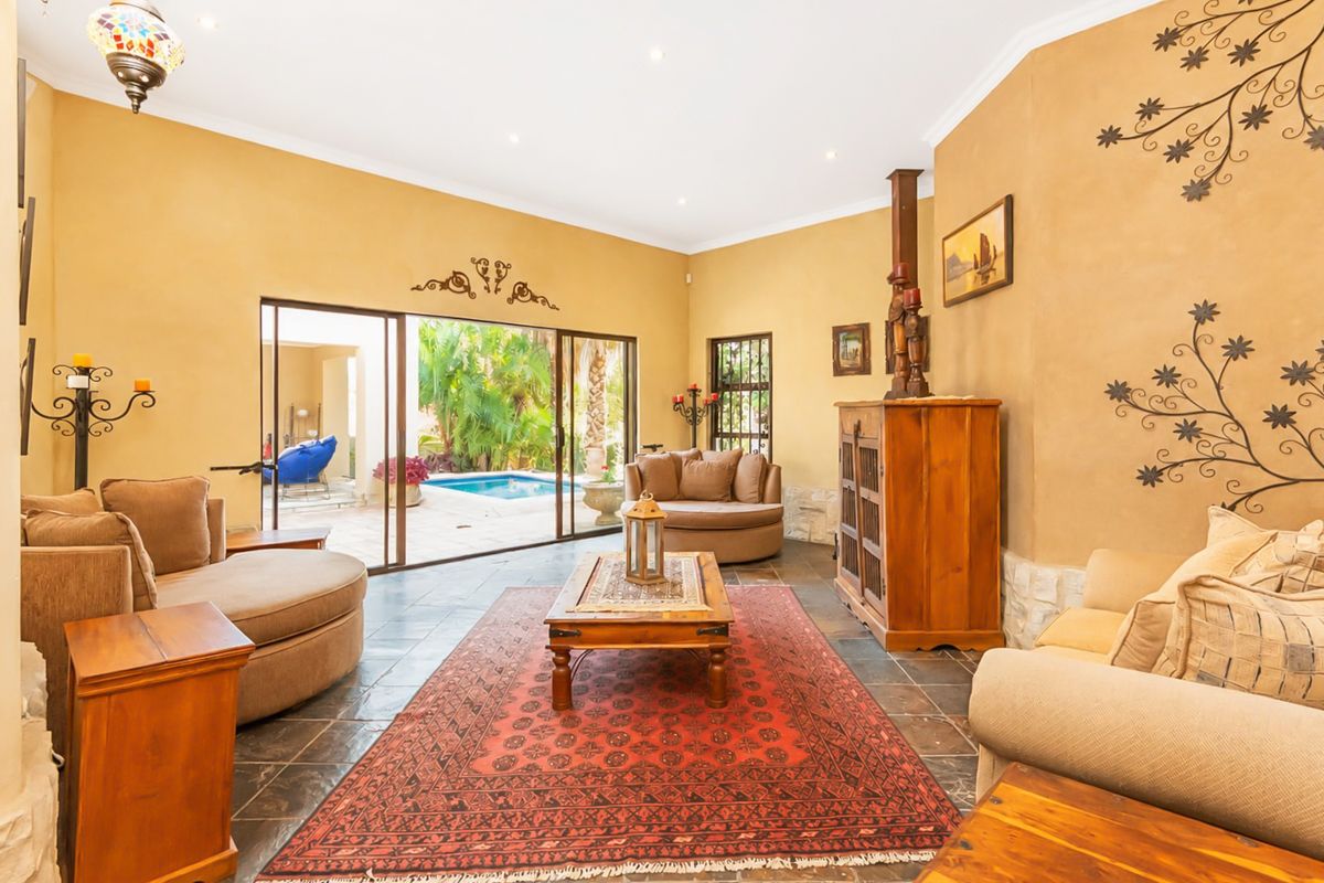 Spacious living room featuring slate tile flooring, textured walls, and large sliding glass doors providing direct access to the outdoor pool area.