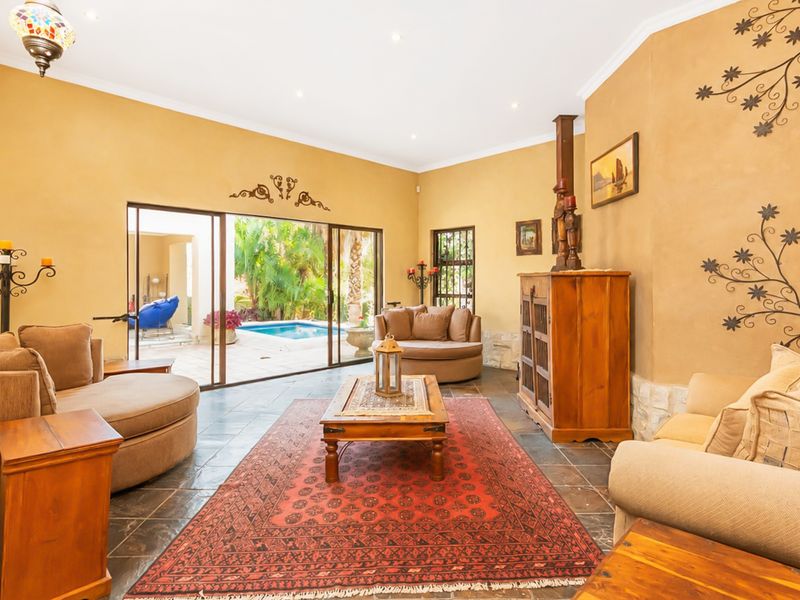 Spacious living room featuring slate tile flooring, textured walls, and large sliding glass doors providing direct access to the outdoor pool area.