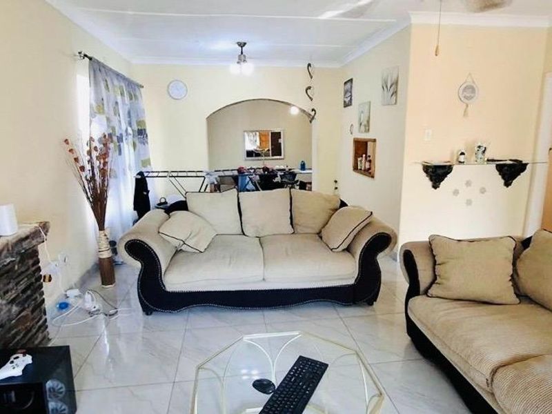 A living room featuring tiled flooring, a stone fireplace, and an arched entryway leading to an adjacent space.