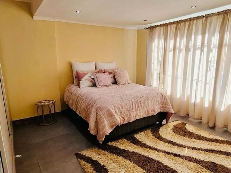 A spacious bedroom featuring tiled flooring, recessed downlighting, and built-in cupboards, offering a comfortable and functional living space.