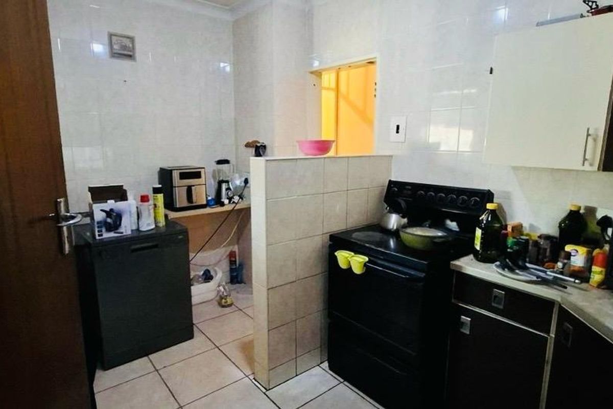 A functional kitchen featuring tiled walls and flooring, built-in cabinetry, and a freestanding stove, offering a practical layout with potential for modern updates.