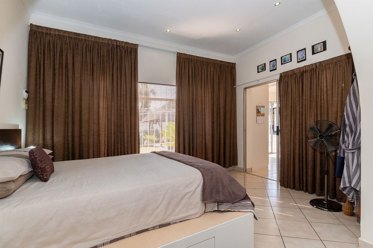 A bedroom featuring tiled flooring, recessed downlighting, and direct access to an adjoining space through a sliding door.