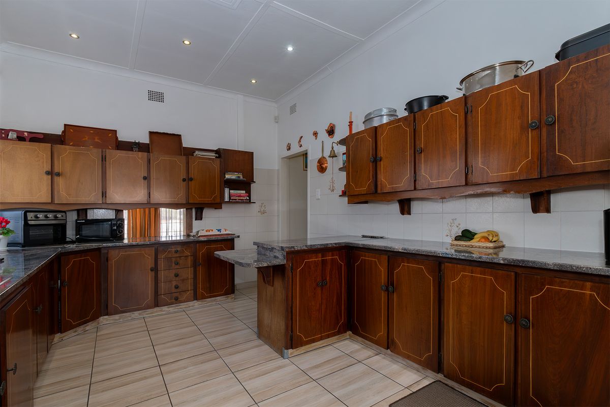 A functional kitchen featuring traditional wooden cabinetry, granite countertops, tiled flooring, and recessed lighting, offering a classic layout with ample storage space.
