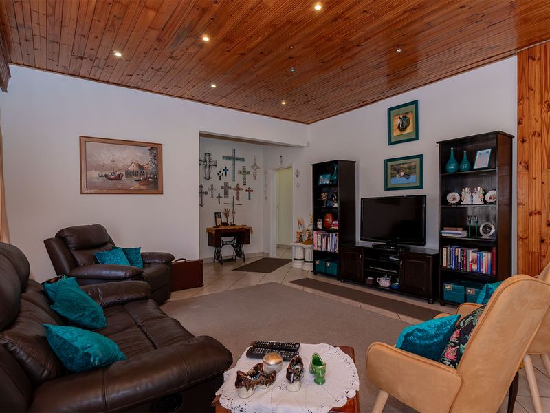Spacious living room featuring a warm timber tongue and groove ceiling with recessed downlighting and neutral tiled flooring.
