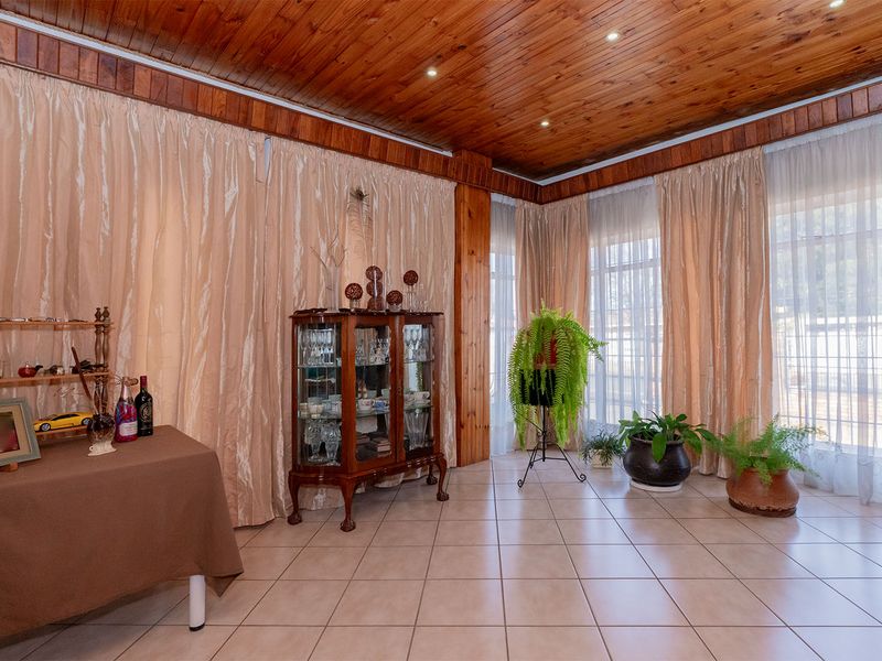 A living area featuring a warm timber-clad ceiling, recessed lighting, and neutral ceramic floor tiles, offering a bright and inviting space.