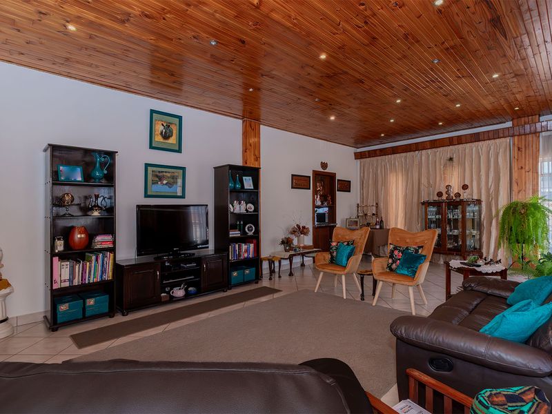Spacious living room featuring a warm timber tongue and groove ceiling with recessed downlights and neutral ceramic floor tiles.