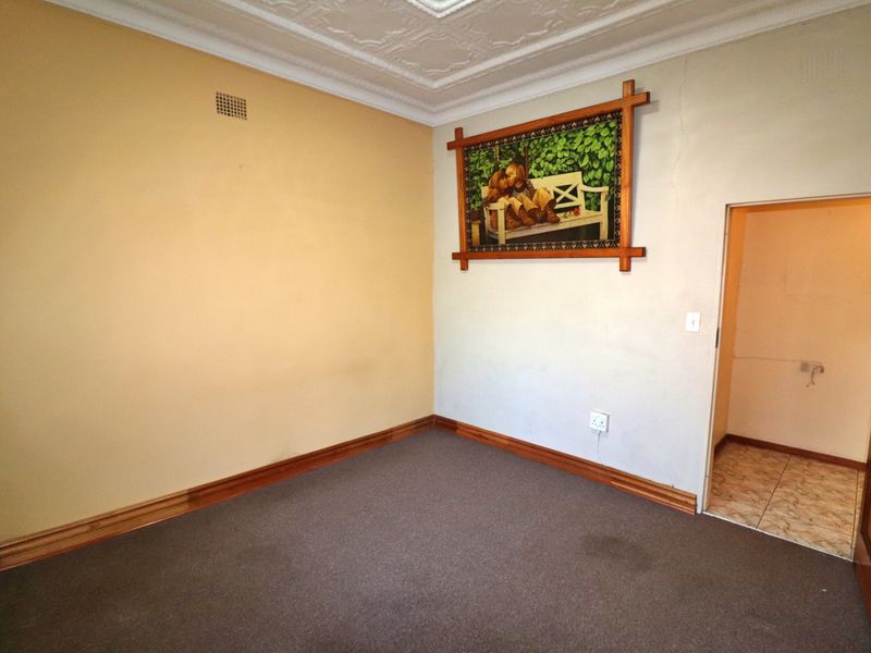 An empty bedroom featuring ornate ceiling detailing, timber skirting boards, and neutral wall tones, offering a blank canvas for renovation or restyling.