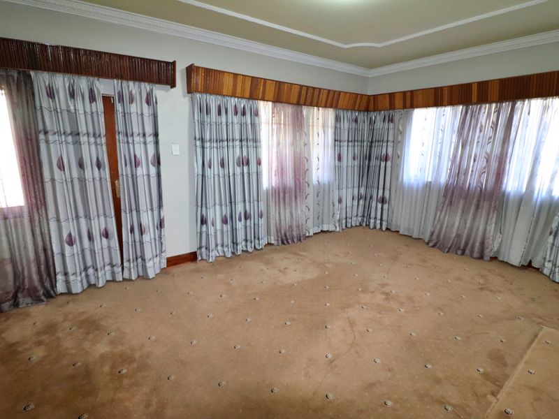 Spacious living area featuring carpeted flooring, coved ceilings, and wooden pelmets, offering a blank canvas for interior design updates.