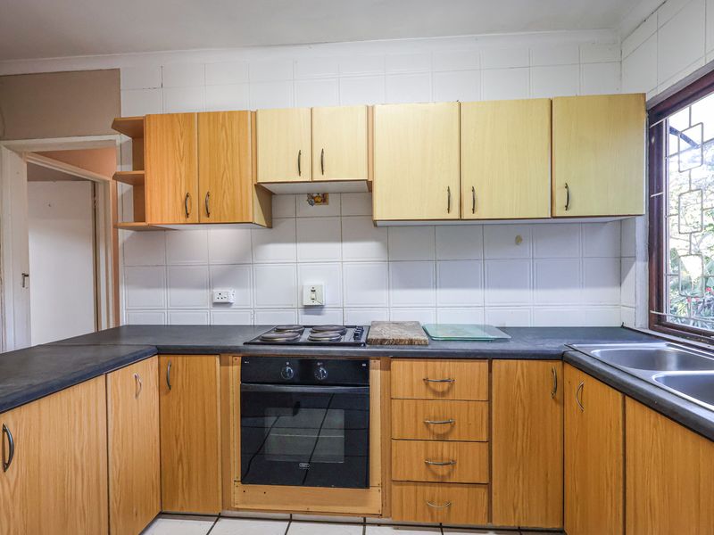 A functional kitchen featuring wooden cabinetry, laminate countertops, a built-in oven, electric hob, and a double bowl sink with tiled backsplash.
