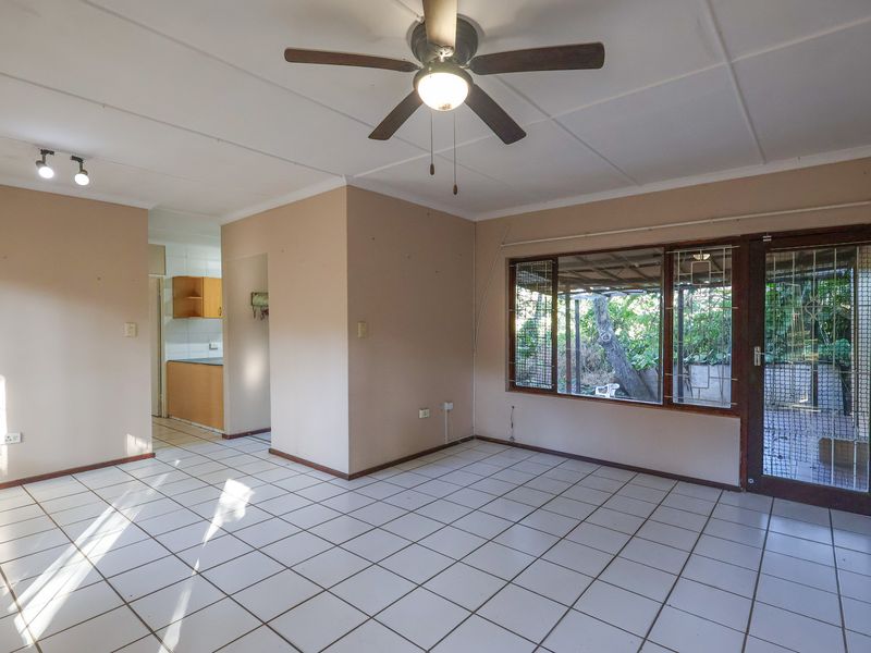Spacious open-plan living area featuring tiled flooring, a ceiling fan, and direct access to an outdoor patio area.