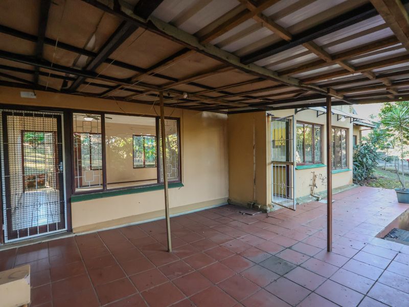 A covered outdoor patio area featuring tiled flooring and security gates, providing direct access to the interior living spaces.