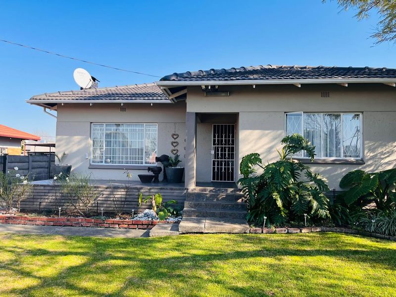 Front elevation of a single-story house featuring a tiled roof, concrete porch, and security gate entrance with a landscaped front garden.