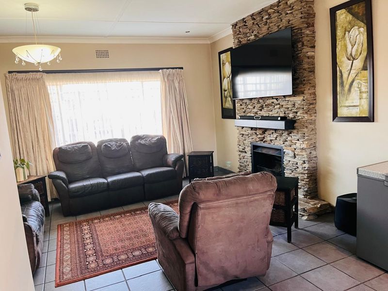 A comfortable living room featuring a prominent stone-clad fireplace, tiled flooring, and neutral wall finishes, creating a warm and inviting atmosphere.
