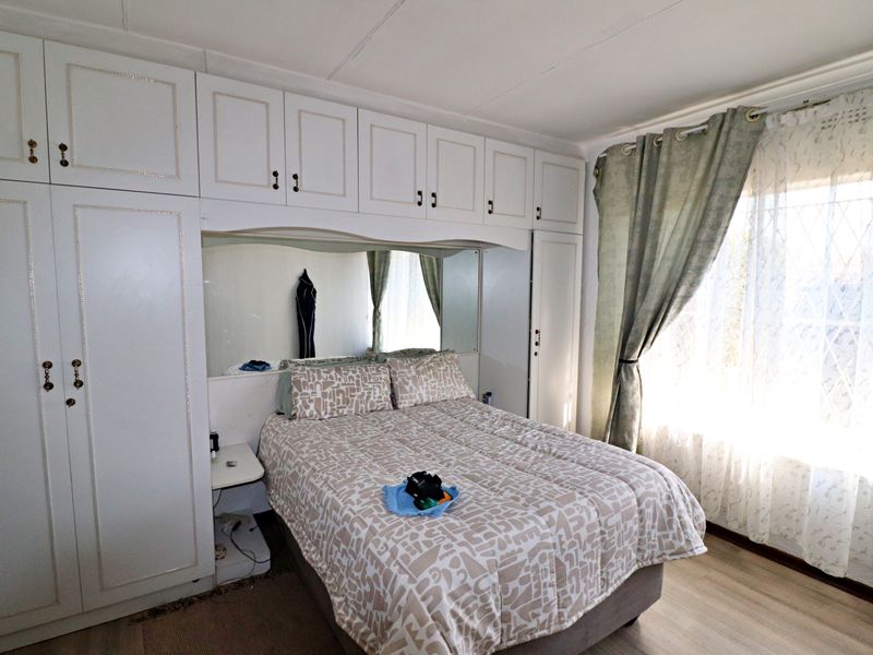A bedroom featuring extensive built-in cabinetry with integrated mirrored headboard and light-toned laminate flooring.