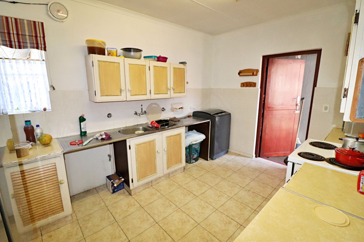 A functional kitchen featuring tiled flooring, built-in cabinetry, a stainless steel sink, and an electric stove, offering potential for modernization.