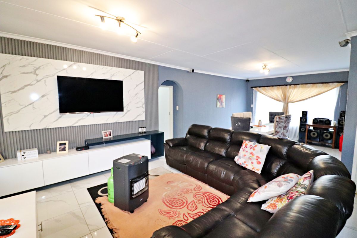 Spacious living room featuring a modern marble-effect media wall, sleek built-in cabinetry, tiled flooring, and an open-plan layout leading to the dining area.