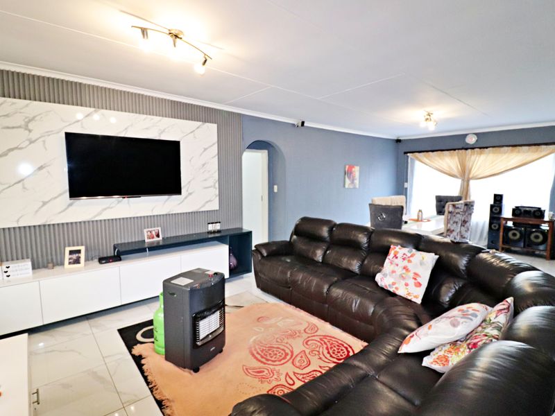 Spacious living room featuring a modern marble-effect media wall, sleek built-in cabinetry, tiled flooring, and an open-plan layout leading to the dining area.