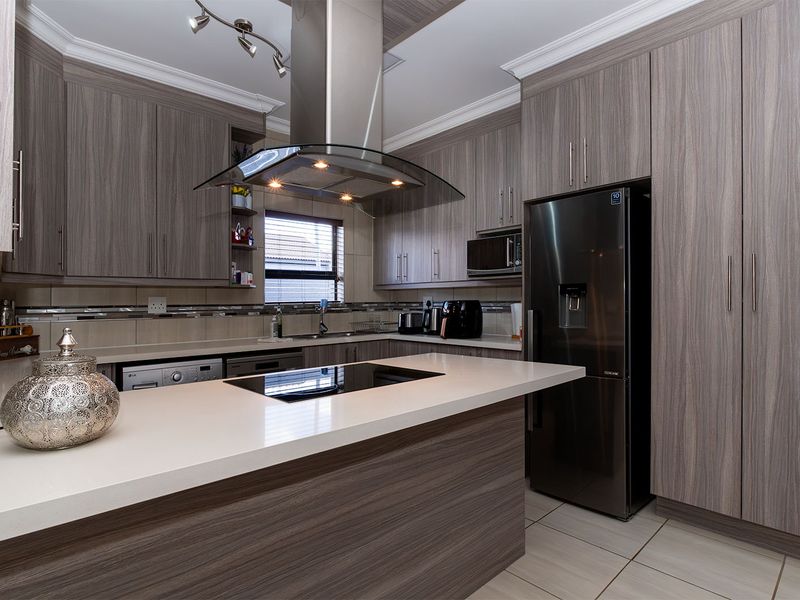Modern kitchen featuring wood-grain cabinetry, stone countertops, integrated hob, stainless steel extractor fan, and high-quality finishes throughout.