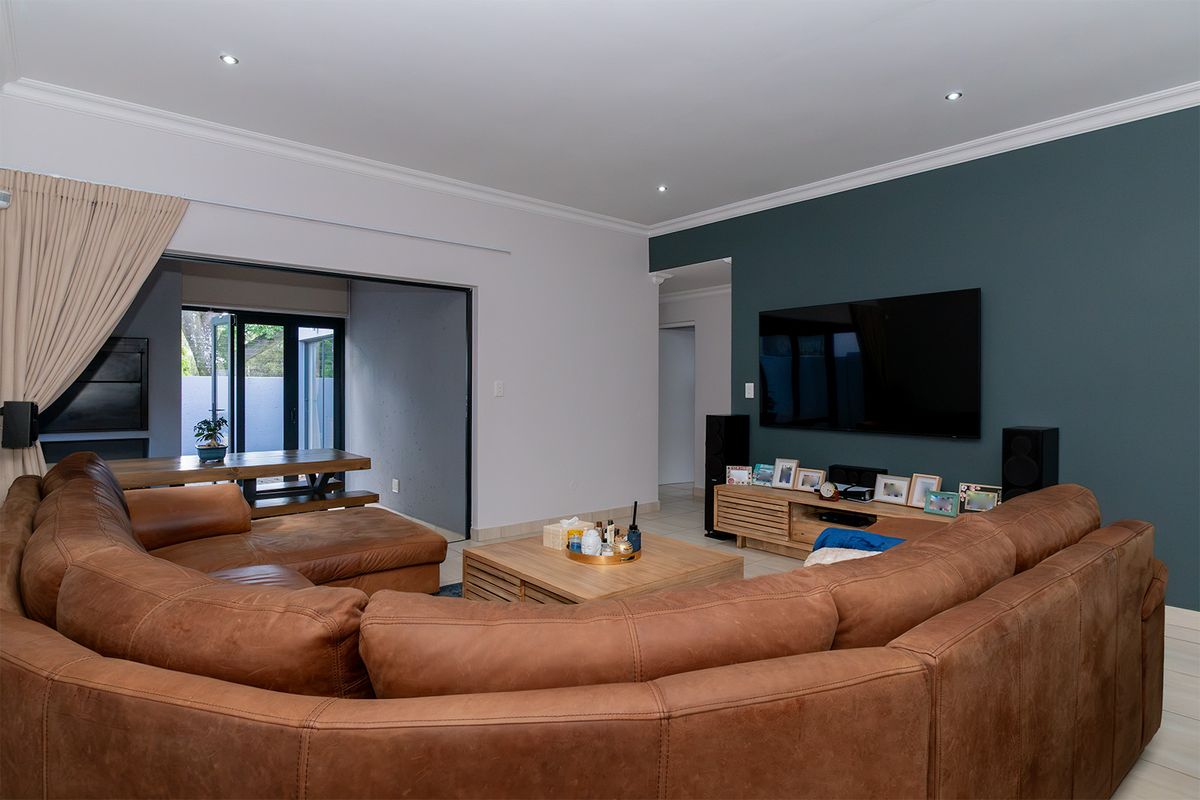 Spacious living room featuring recessed downlights, crown molding, and large sliding glass doors that provide seamless access to the outdoor patio area.