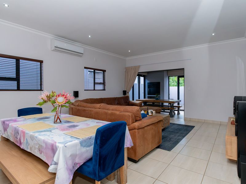 Spacious open-plan living and dining area featuring tiled flooring, recessed lighting, and direct access to an outdoor patio through sliding glass doors.